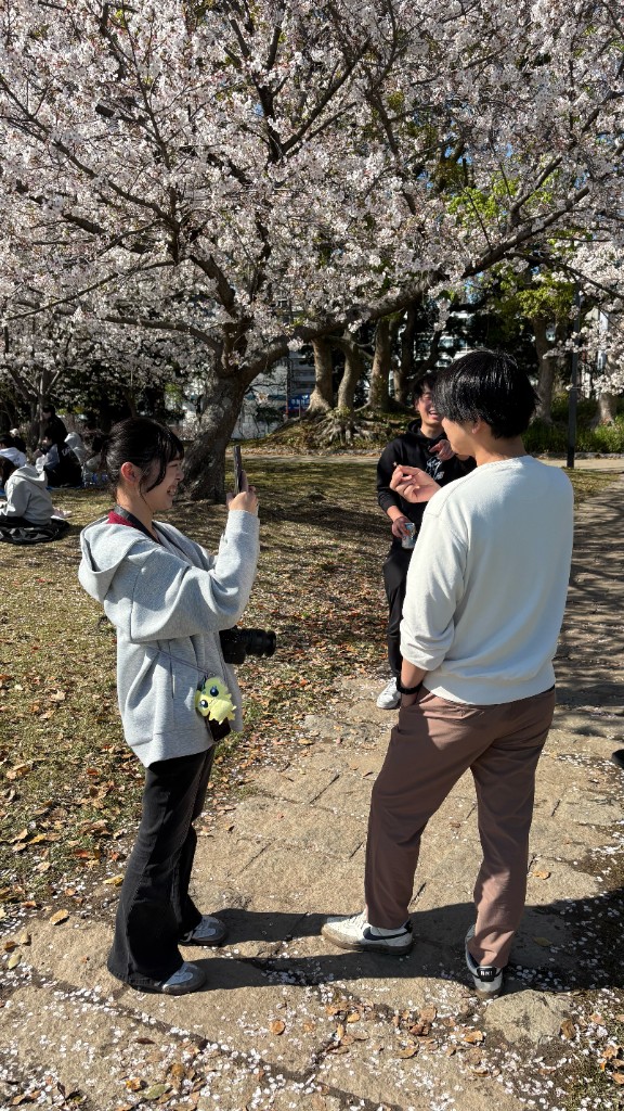 桜の下で撮影するメンバー